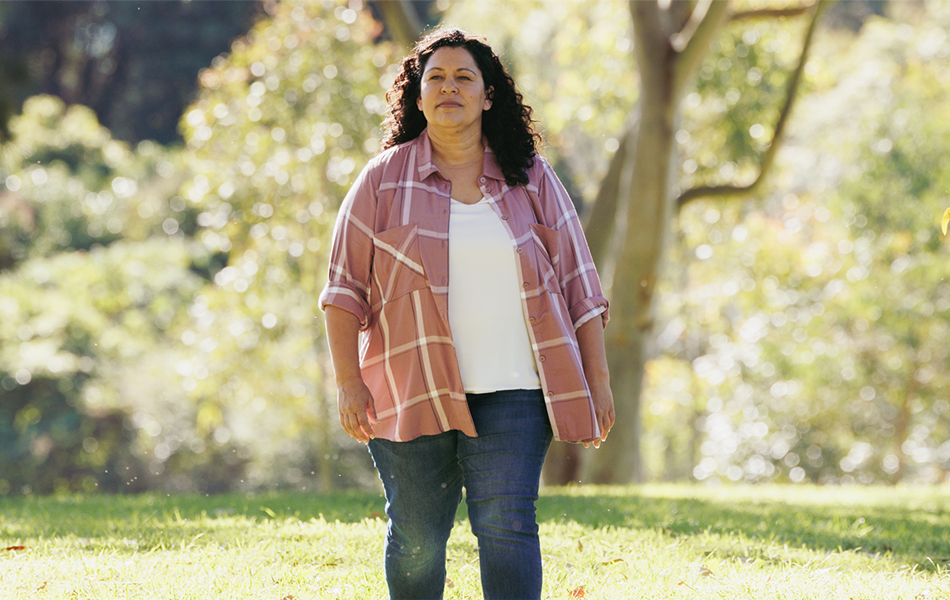 Woman in cardigan walking towards the camera in a park